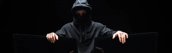 Panoramic shot of hacker touching computer monitors isolated on black — Stock Photo