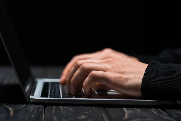 Cropped view of hacker typing on laptop keyboard isolated on black — Stock Photo