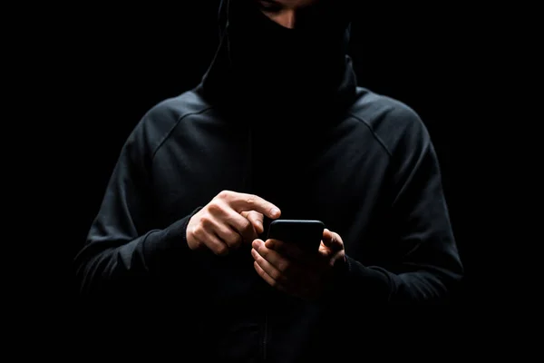 Cropped view of hacker pointing with finger at smartphone isolated on black — Stock Photo