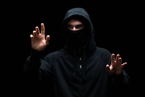 Hacker anônimo no capuz gesticulando isolado no preto — Stock Photo