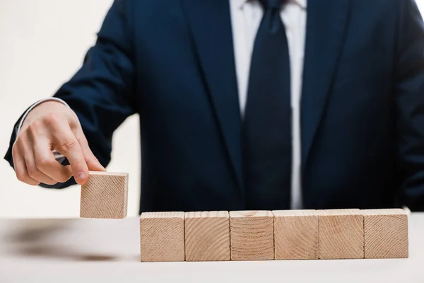 Vista recortada de hombre de negocios en traje tomando cubos de madera aislados en blanco - foto de stock