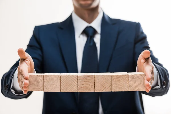 Vue recadrée de l'homme d'affaires en costume tenant des cubes en bois isolés sur blanc — Photo de stock