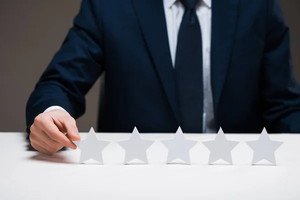 Cropped view of businessman touching star isolated on grey, quality concept — Stock Photo