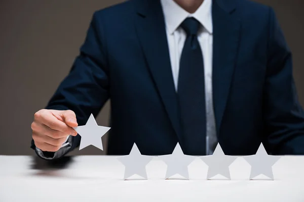 Cropped view of businessman holding star isolated on grey, quality concept — Stock Photo