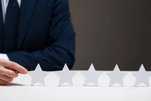 Abgeschnittene Ansicht eines Geschäftsmannes im Anzug, der den Stern auf grauem Grund berührt, Qualitätskonzept — Stockfoto