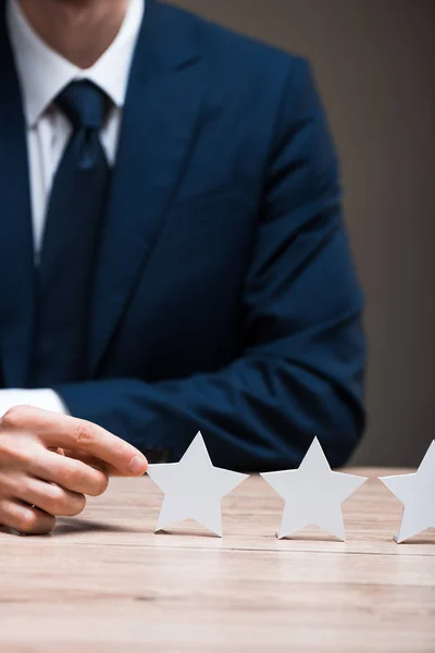 Cropped view of man in formal wear touching star isolated on grey, quality concept — Stock Photo