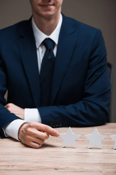 Ausgeschnittene Ansicht eines glücklichen Geschäftsmannes in formaler Kleidung, der den Stern berührt, isoliert auf grau, Qualitätskonzept — Stockfoto