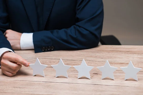 Abgeschnittene Ansicht eines Geschäftsmannes in formaler Kleidung, der den Stern berührt, isoliert auf grau, Qualitätskonzept — Stockfoto