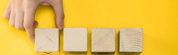 Tiro panorâmico homem segurando cubo de madeira isolado no amarelo — Fotografia de Stock