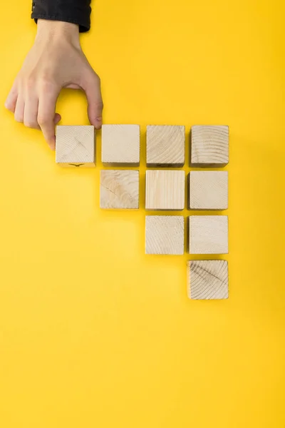 Vue de dessus de l'homme touchant cube en bois isolé sur jaune — Photo de stock