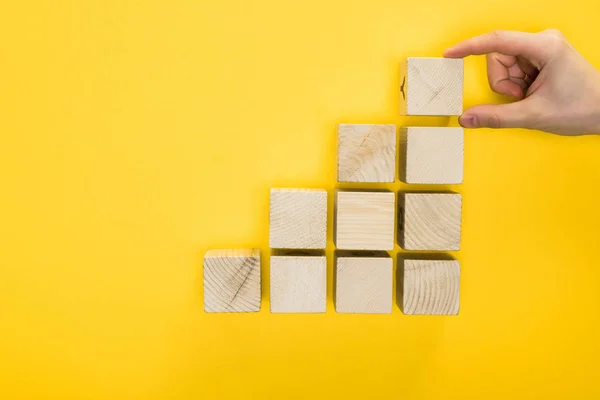 Top view of man holding wooden cube isolated on yellow — Stock Photo