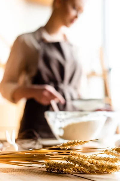 Foco seletivo de trigo perto da mulher cozinhar na cozinha — Fotografia de Stock