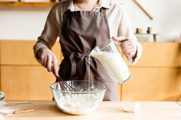 Abgeschnittene Ansicht einer Frau, die Milch in eine Schüssel mit Mehl gießt — Stockfoto