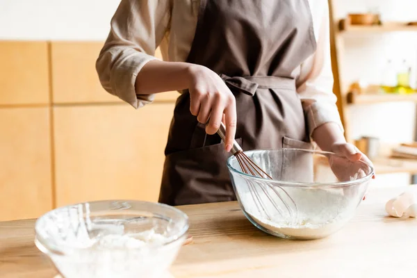 Abgeschnittene Ansicht eines Mädchens, das Schneebesen in der Nähe einer Schüssel mit Mehl hält — Stockfoto