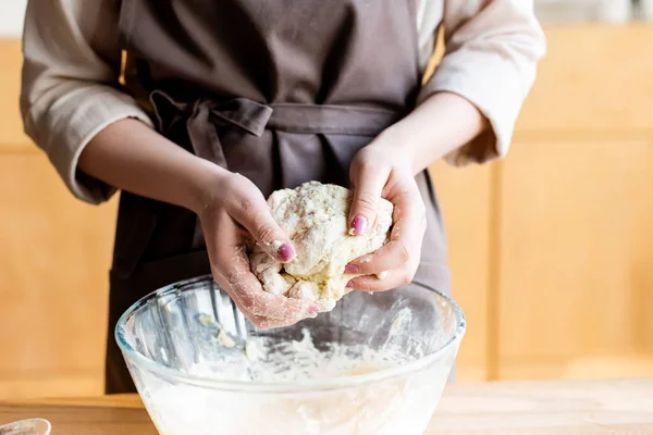 Cropped view of woman in apron holding dough in hands — Stock Photo