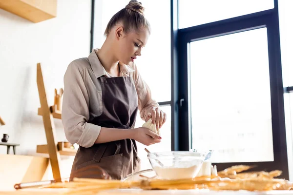 Selective focus of woman in apron holding dough in hands — Stock Photo