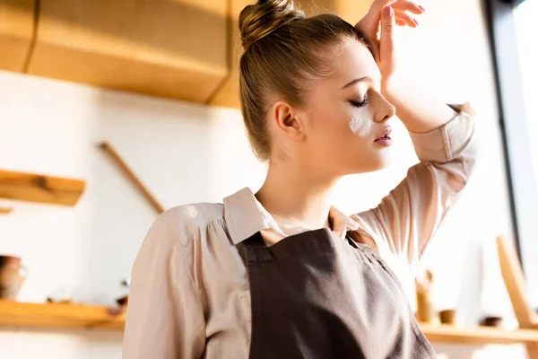 Young tired woman with flour on face touching forehead — Stock Photo