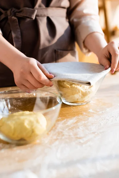 Cropped view of woman covering dough in bowl with towel — Stock Photo