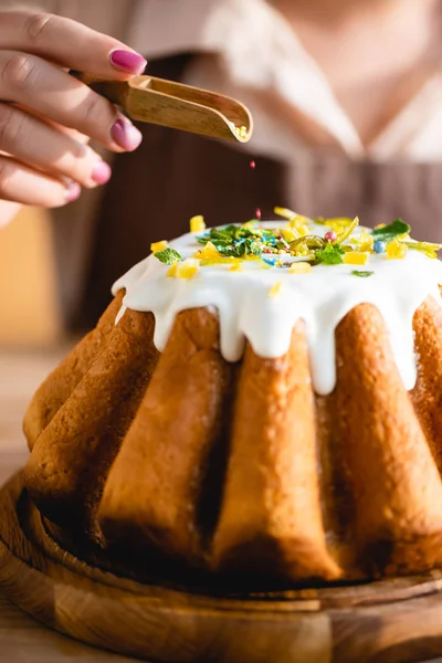 Vue recadrée de fille tenant cuillère avec des aspersions près de gâteau de Pâques savoureux — Photo de stock