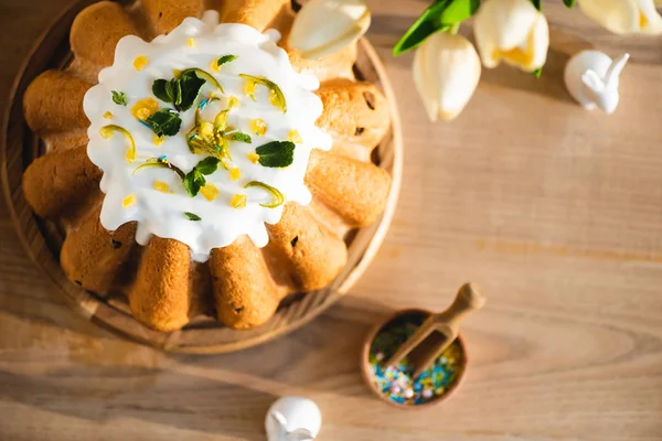 Vue de dessus du gâteau de Pâques savoureux près des figurines avec des lapins de Pâques décoratifs et des tulipes — Photo de stock