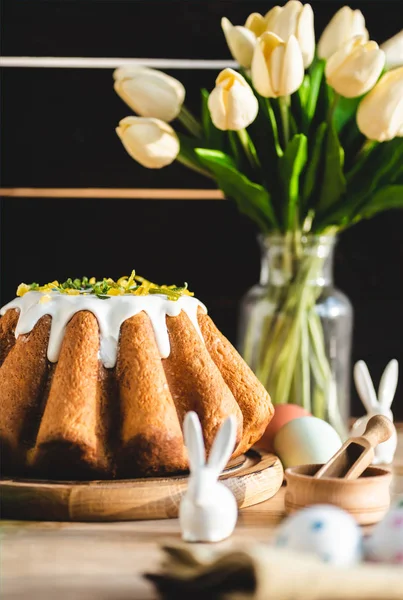 Selective focus of delicious easter cake near tulips, figurines with easter bunnies and painted eggs — Stock Photo