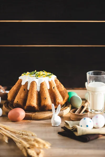 Fuoco selettivo di torta pasquale vicino a vetro di latte, statuetta con coniglio e uova dipinte — Foto stock