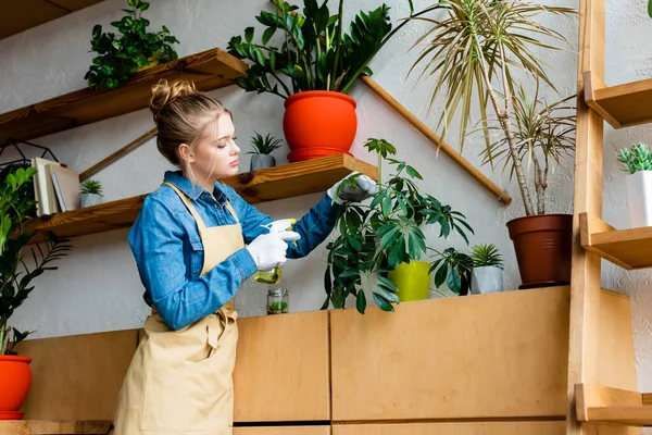 Hermosa mujer sosteniendo botella de spray cerca de plantas - foto de stock