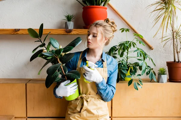 Bella donna in possesso di bottiglia spray e pianta verde — Foto stock