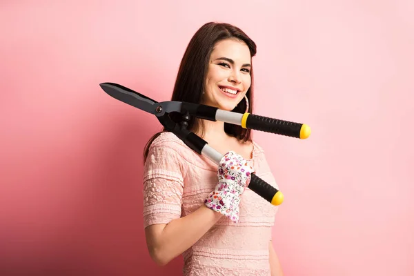 Alegre chica en trabajo guantes celebración jardinería tijeras sobre rosa fondo - foto de stock