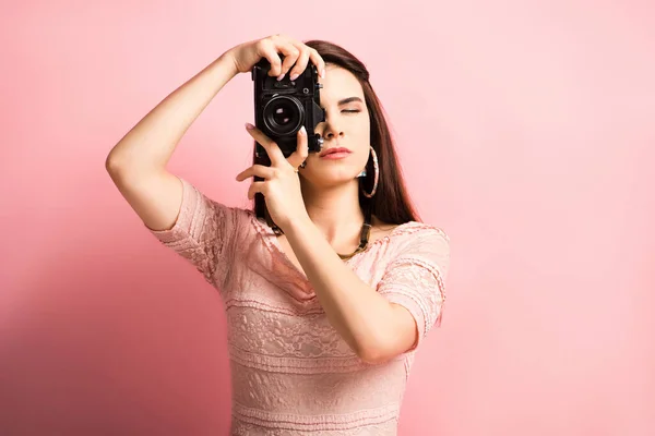 Schöne Fotografin, die Foto auf Digitalkamera auf rosa Hintergrund — Stockfoto