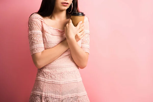 Vista recortada de chica molesta sosteniendo café para ir mientras está de pie sobre fondo rosa - foto de stock