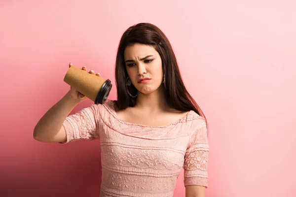 Displeased girl showing empty paper cup while looking at camera on pink background — Stock Photo