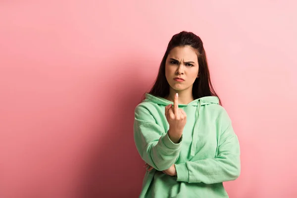 Irritated girl showing middle finger while looking at camera on pink background — Stock Photo