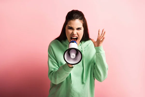 Irritated girl showing indignation gesture while shouting in megaphone on pink background — Stock Photo