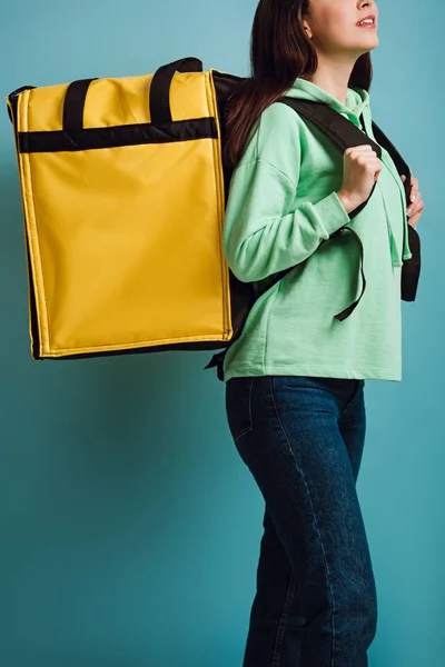 Vista ritagliata della donna di consegna che trasporta zaino termico giallo su sfondo blu — Foto stock