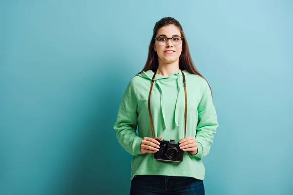 Fotógrafo animado segurando câmera digital no fundo azul — Fotografia de Stock