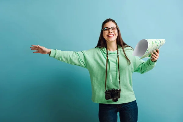 Allegro turista con macchina fotografica digitale fermo auto tenendo la mappa su sfondo blu — Foto stock