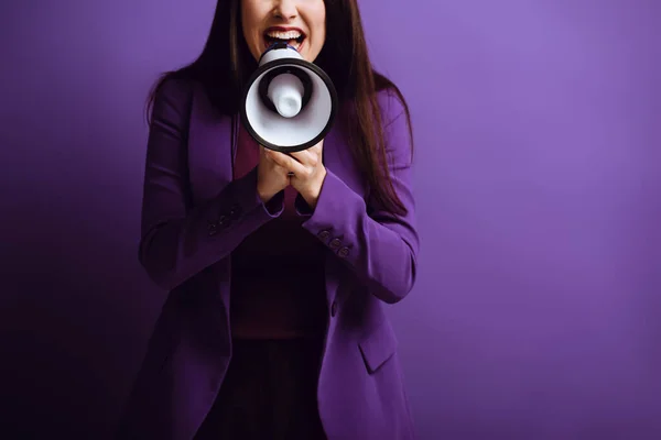 Vista cortada de mulher excitada gritando em megafone no fundo roxo — Fotografia de Stock