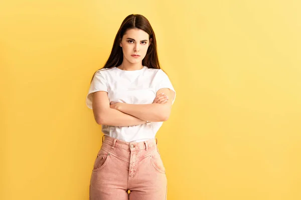 Offensé fille debout avec les bras croisés et regardant caméra isolé sur jaune — Photo de stock