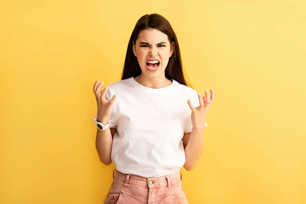 Irritated girl gesturing and shouting while showing indignation gesture isolated on yellow — Stock Photo