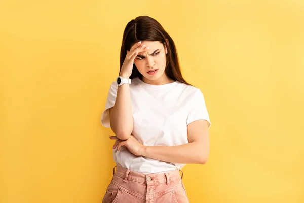 Tired, upset girl touching head while suffering from headache isolated on yellow — Stock Photo