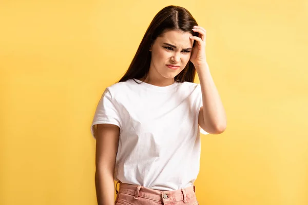 Exhausted girl touching head while suffering from headache isolated on yellow — Stock Photo