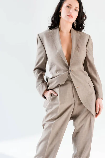 Stylish and sexy woman in suit looking at camera on grey background — Stock Photo