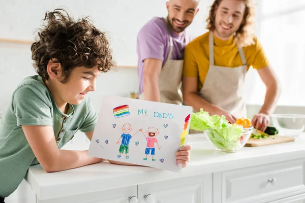 Foyer sélectif d'enfant métis tenant l'image avec mes papas lettrage près heureux parents homosexuels — Photo de stock