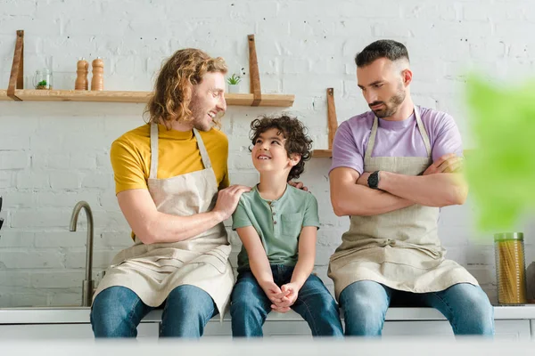 Messa a fuoco selettiva di bei genitori omosessuali guardando figlio razza mista — Foto stock