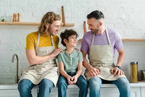 Enfoque selectivo de padres homosexuales felices mirando al hijo de raza mixta - foto de stock