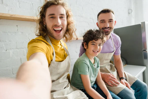 Enfoque selectivo de los hombres homosexuales guapos sonriendo con lindo niño de raza mixta - foto de stock