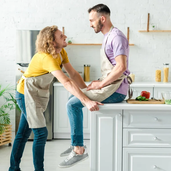 Vista lateral de los hombres homosexuales felices mirándose entre sí - foto de stock