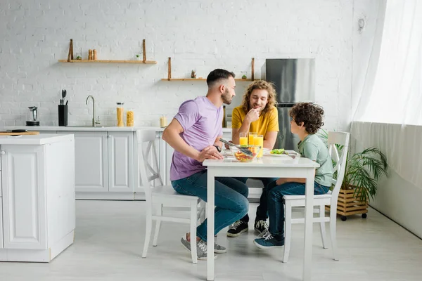 Homosexual parents and cute mixed race son having lunch at home — Stock Photo