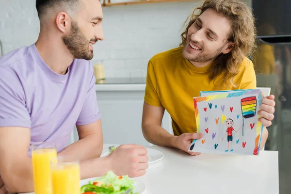 Foyer sélectif des hommes homosexuels heureux regardant les uns les autres près de dessin sur papier — Photo de stock